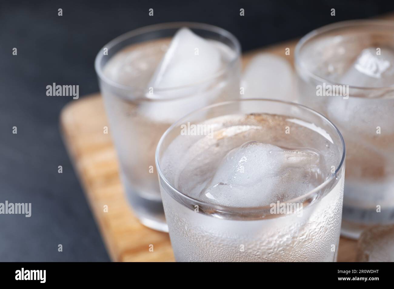 Shot glasses of vodka with ice cubes on table, closeup Stock Photo