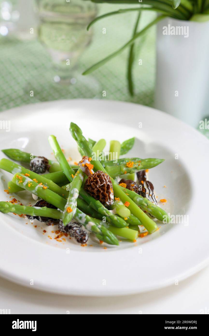 Green asparagus in creamy sauce with morels and finely chopped orange rinds Stock Photo