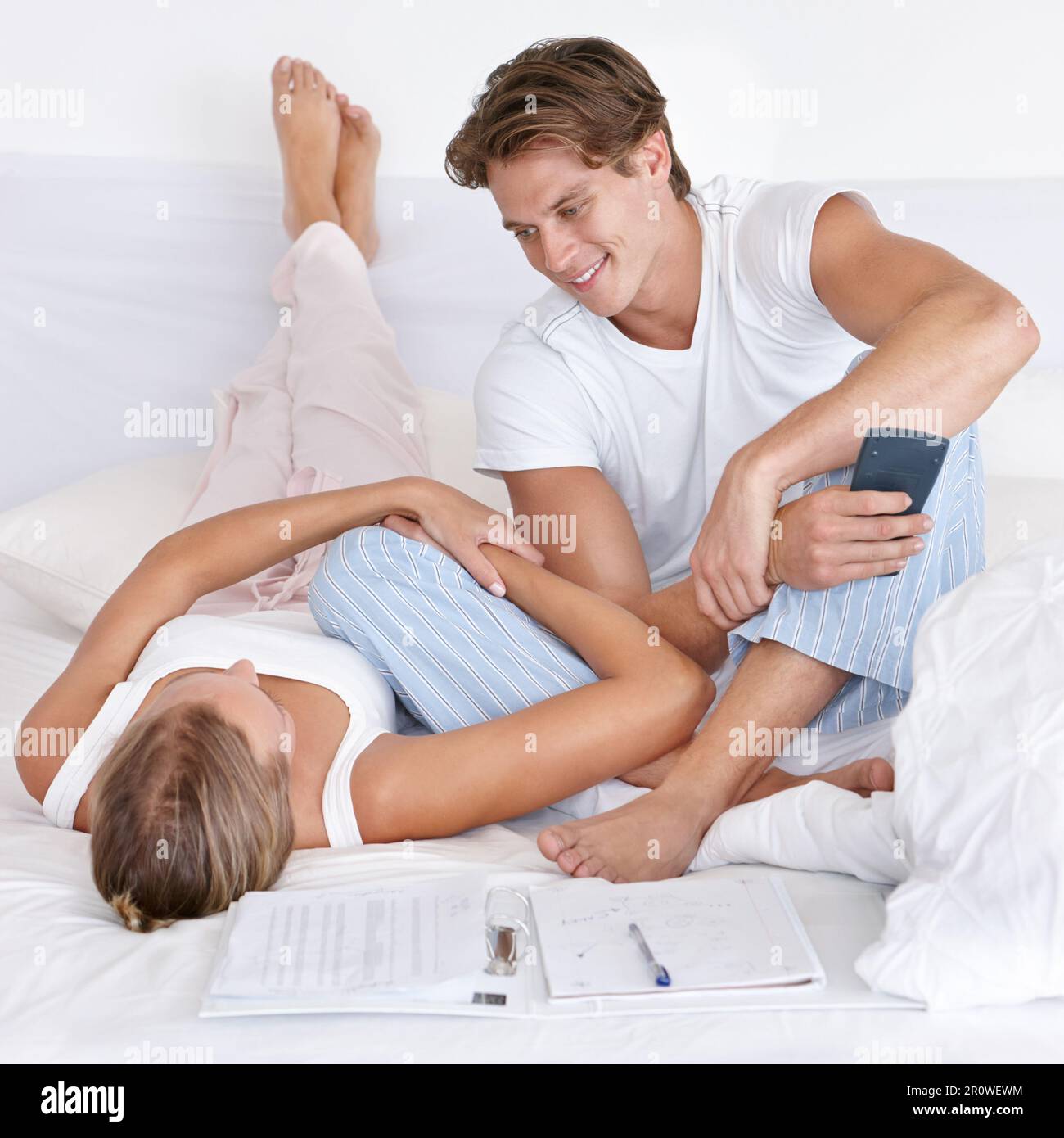 Man, woman and bedroom with calculator, budget and planning finance for saving, investment or debt in home. Couple, tax and happiness for profit Stock Photo