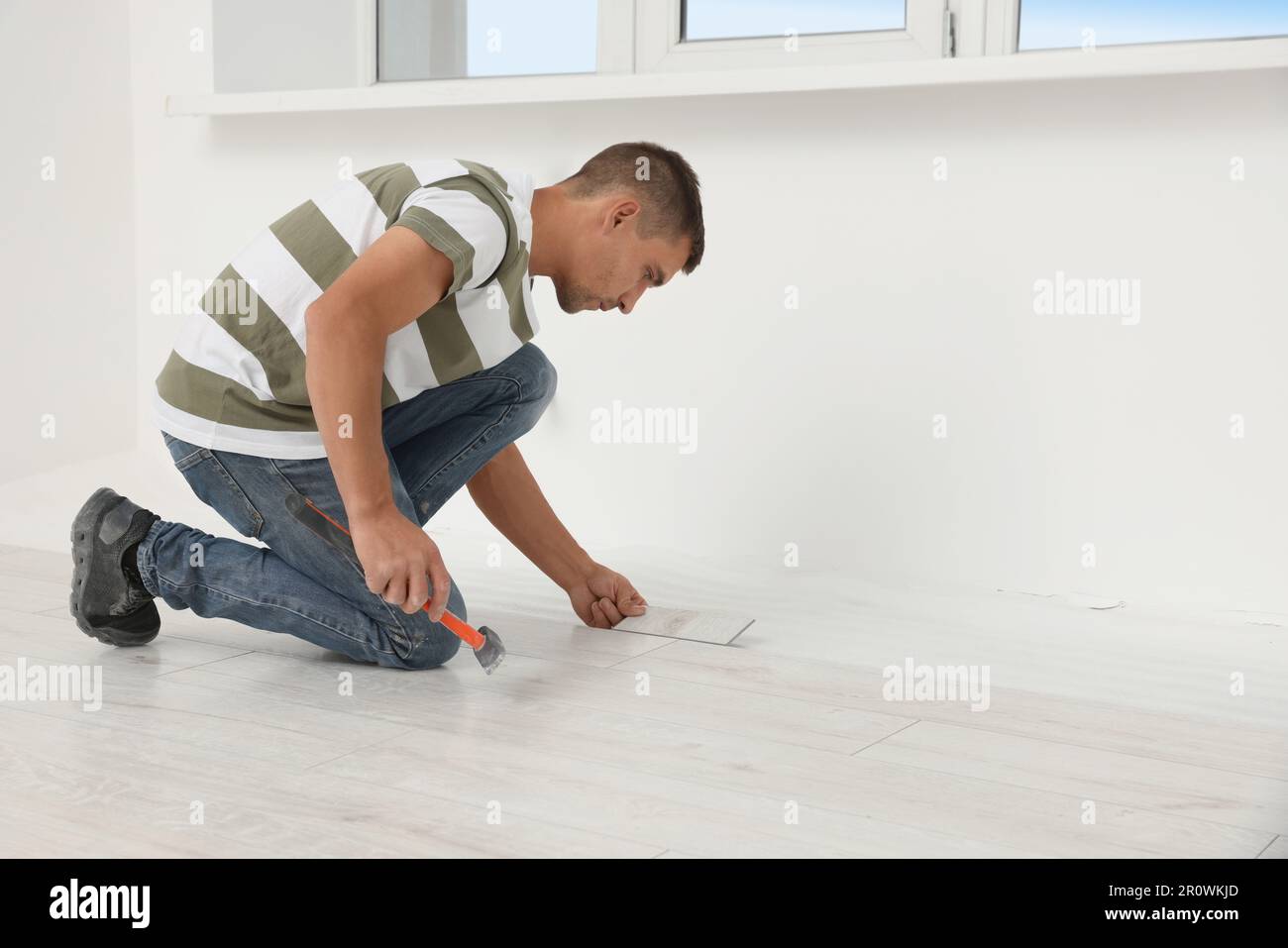 Professional worker using hammer during installation of new laminate