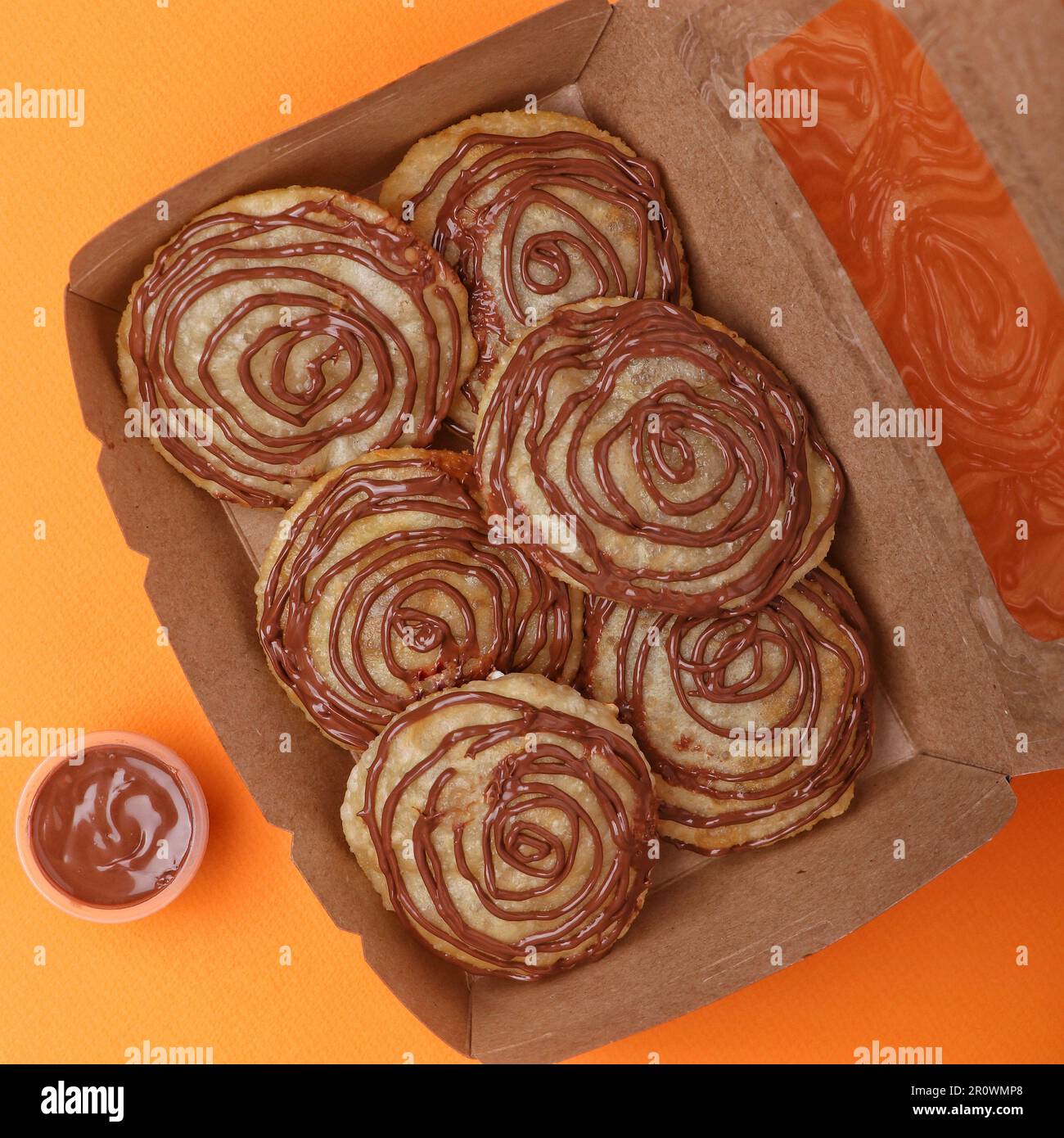 cookies with chocolate and caramel in a paper box on an orange background Stock Photo
