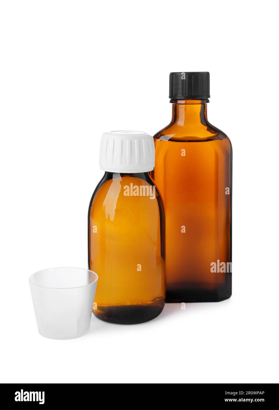 Bottles of syrups with measuring cup on white background. Cough and