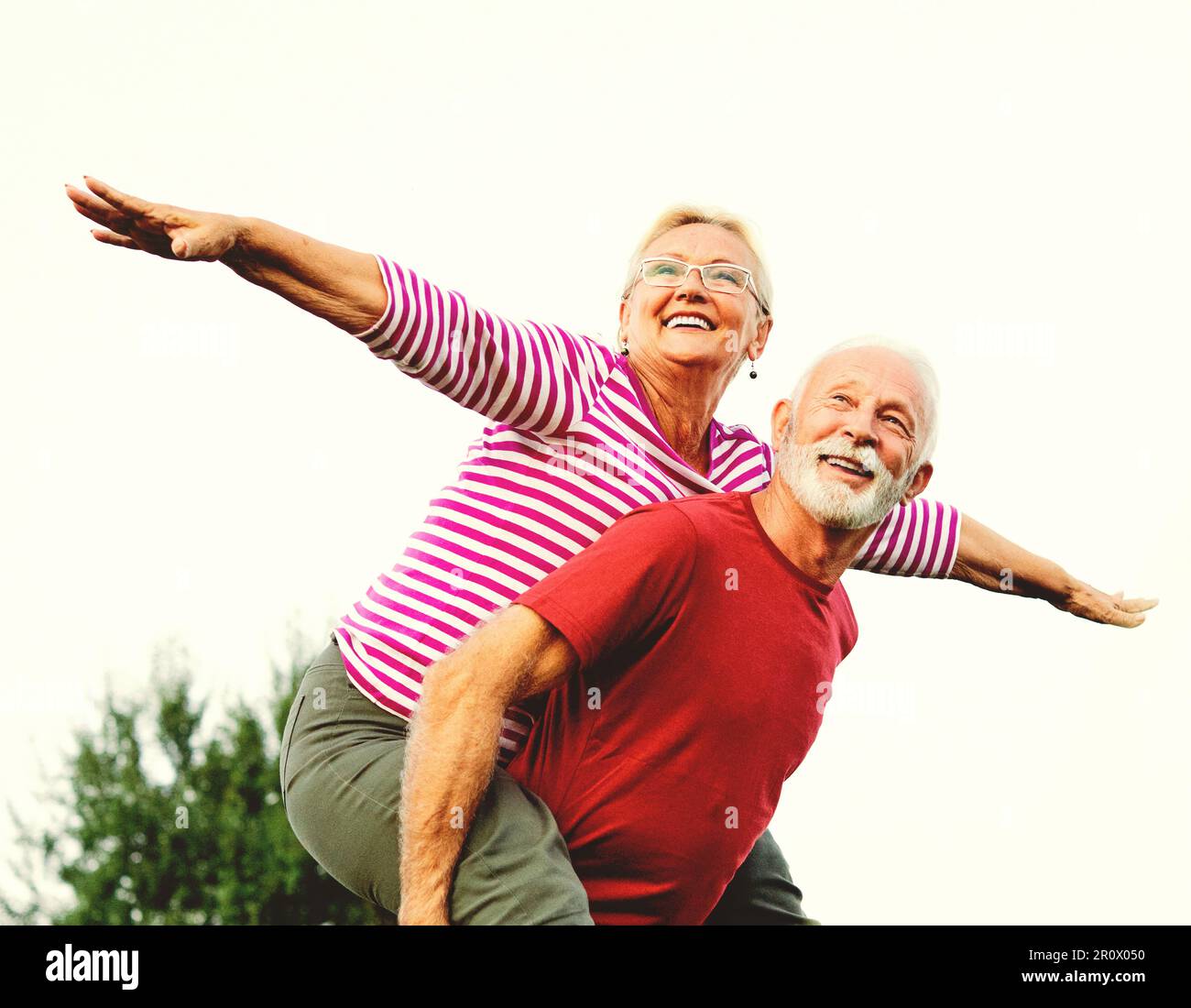 woman man outdoor senior couple happy lifestyle retirement together smiling love piggyback active mature Stock Photo