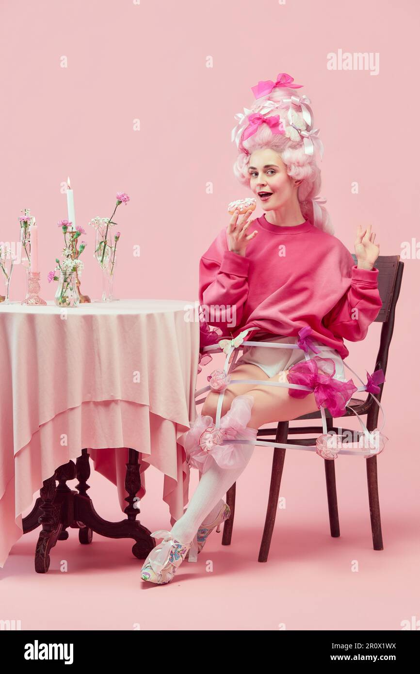Portrait gorgeous princess, queen wearing big pink wig holding donut