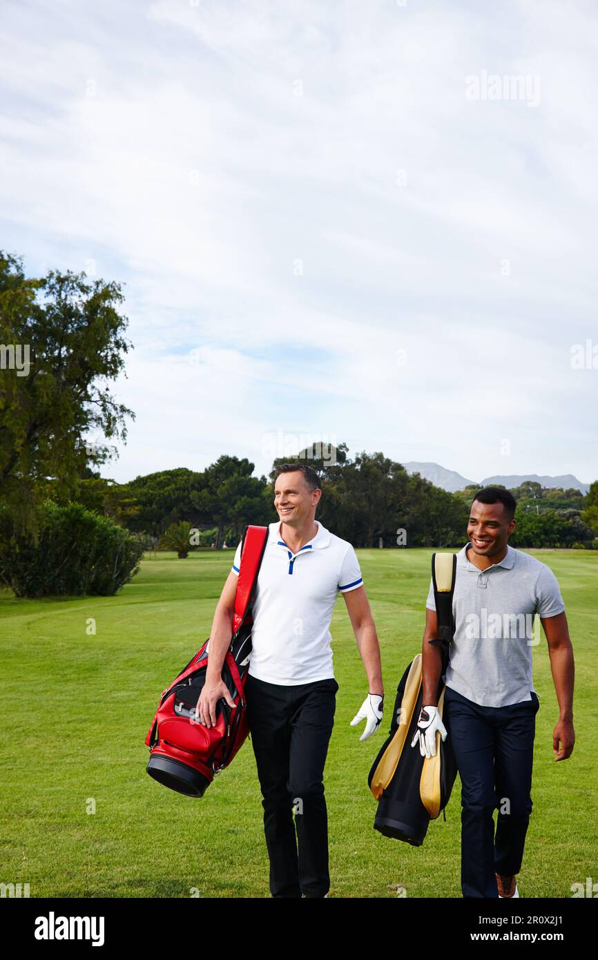Fun and exercise. two men walking across a golf course with their golf bags. Stock Photo