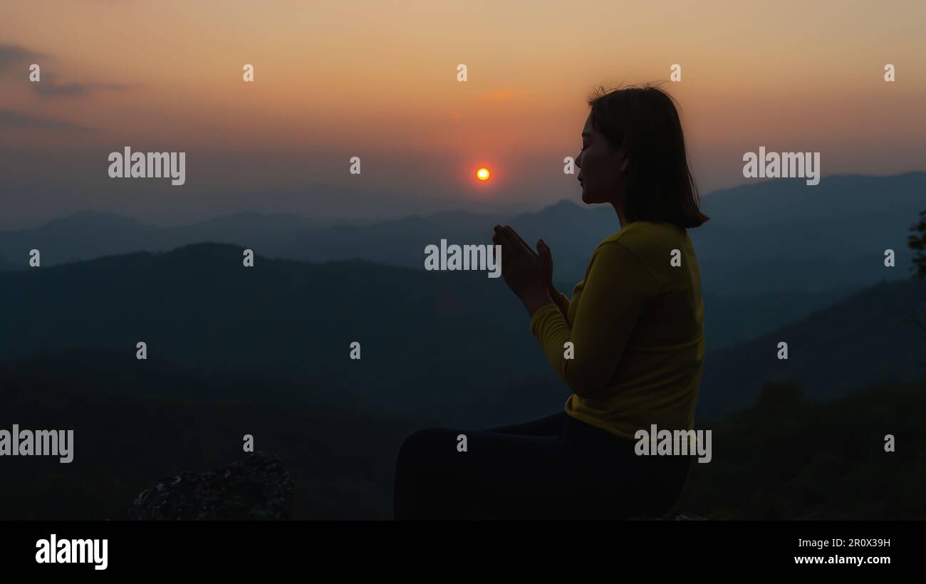 Christian woman praying worship at sunset. Hands folded in prayer. worship god with christian concept religion. Stock Photo