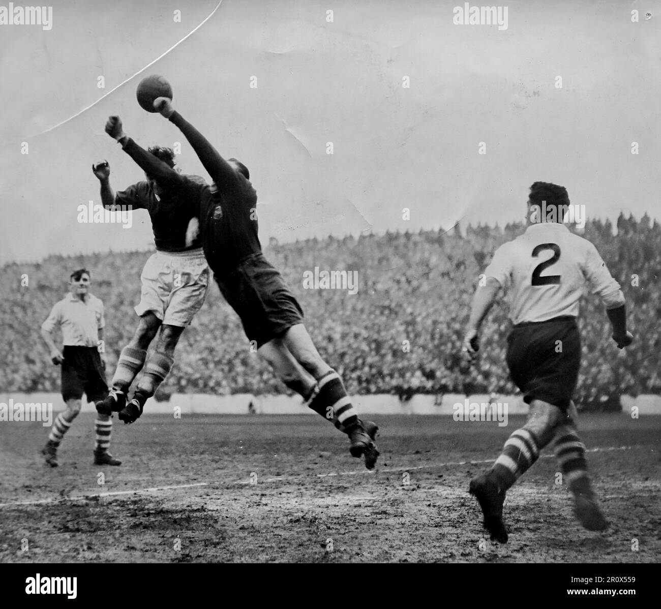 Association football photo, unattributed agency photo, December 30th, 1950. An action shot from the match between Cardiff City and Preston North End, at Ninian Park. City lost 0-2. The photo shows Cardiff winger George Edwards challenging the Preston goalkeeper Jimmy Gooch, with Tommy Docherty watching on. Some surface creasing on the original. Stock Photo