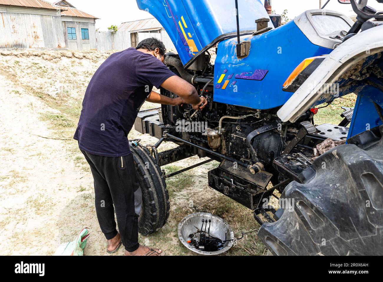 Farmer mechanic repairing blue tractor engine. Combine machine service