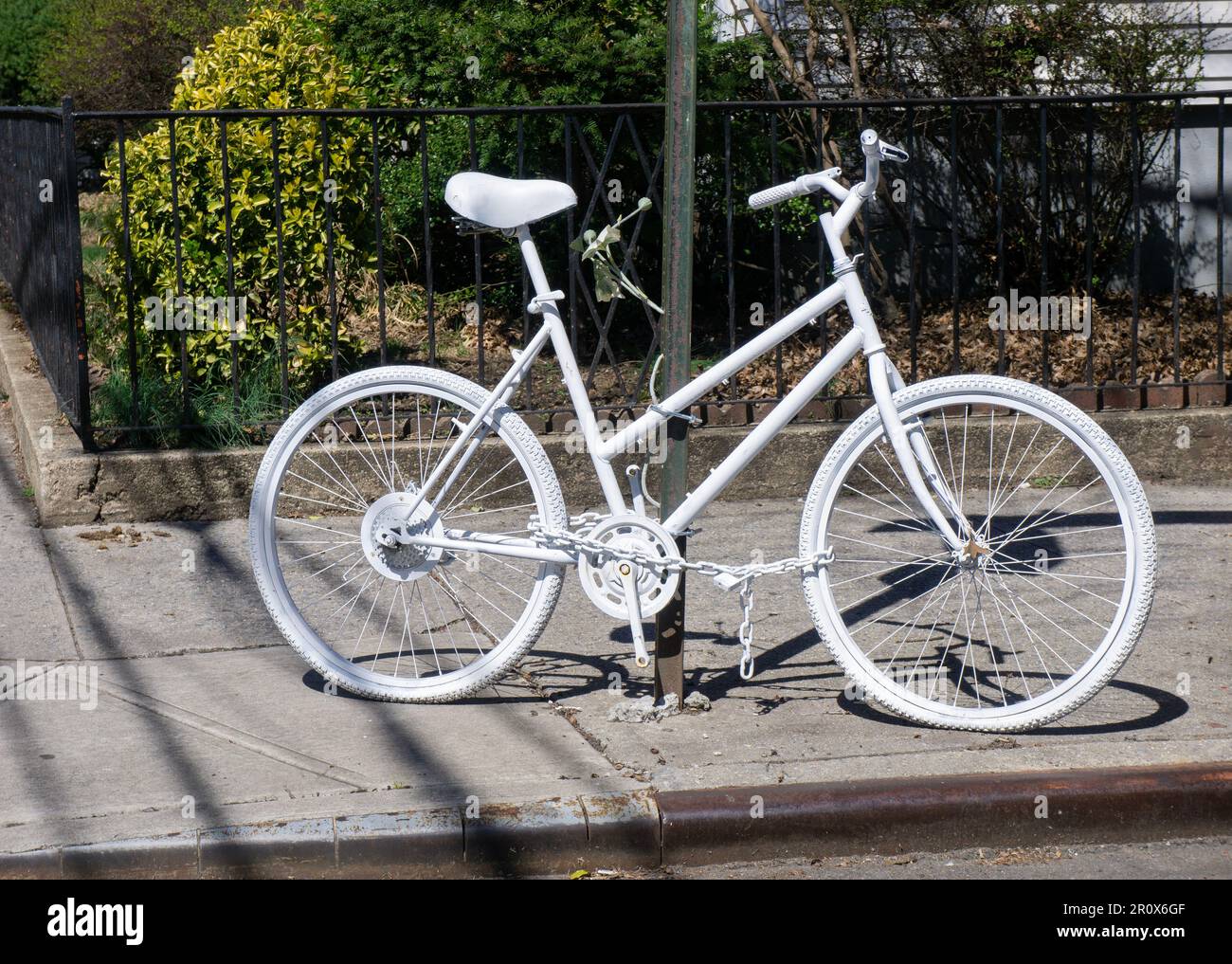A completely white bicycle, a Ghost Bike  installed to commemorate a fatal bike crash. This on is 94th St & 40th Drive in Elmhurst, Queens, New York. Stock Photo