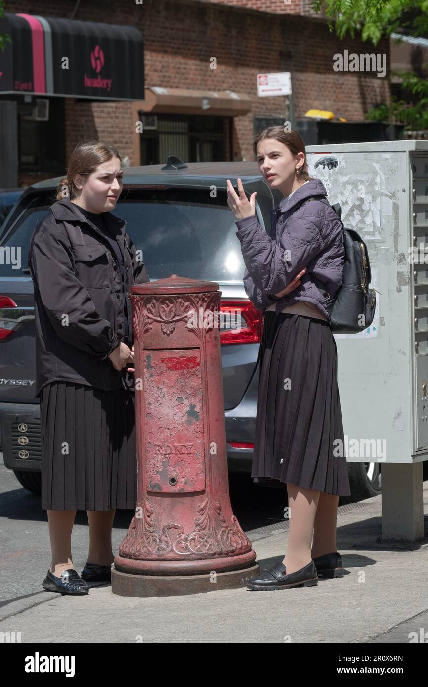 2 modestly dresses orthodox Jewish students have an after-school conversation on a street in Brooklyn, New York. Stock Photo