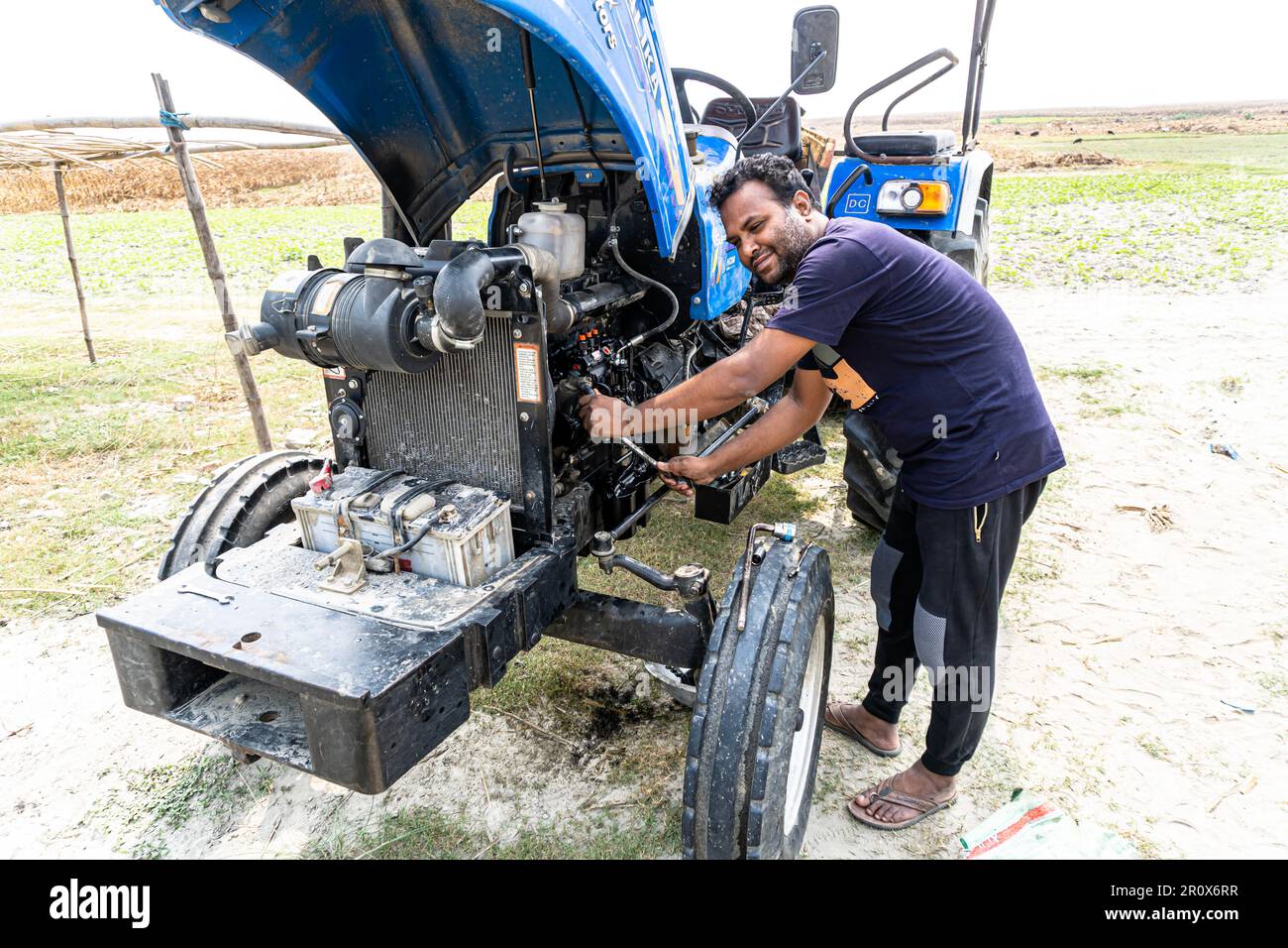 Open hood tractor. Agricultural Equipment Mechanic working on blue