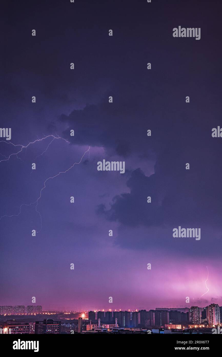 A bright electric bolt of lightning strikes the sky above a modern ...