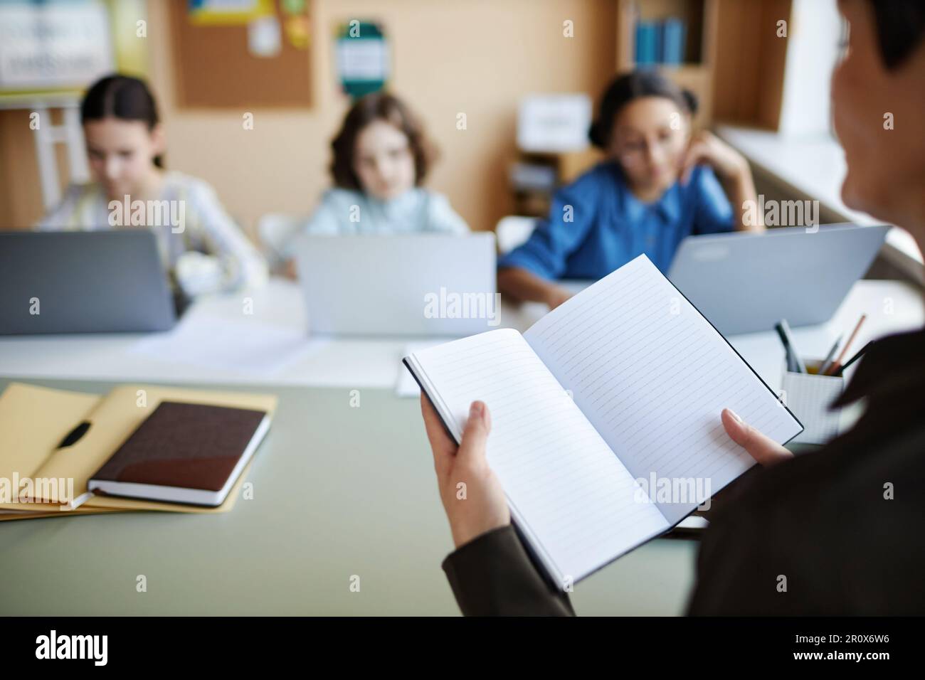 Closeup of teacher opening her notebook and giving homework to