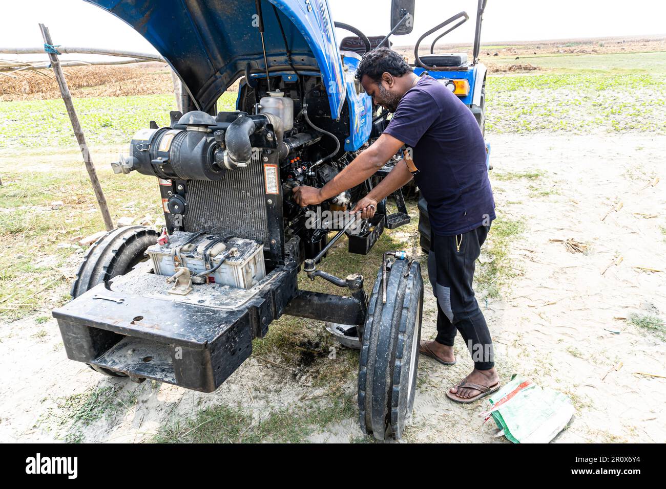 Close up view of hydraulic pipes of heavy industry machine. Open hood tractor. Agricultural Equipment Mechanic working on blue tractor Stock Photo