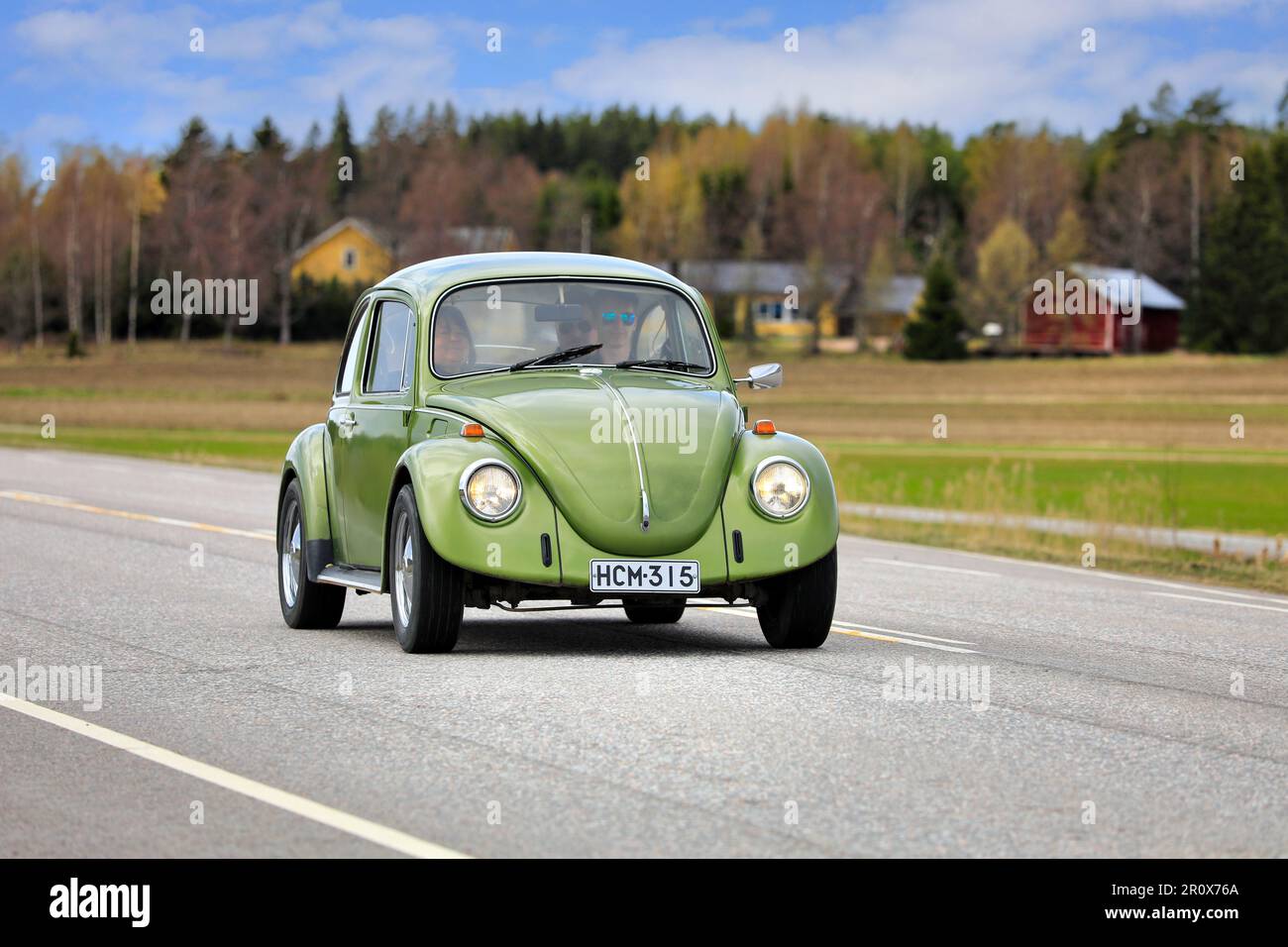 Green 1974 Volkswagen Beetle, officially Volkswagen Type 1, driving along Highway 110 on May Day car cruising event. Salo, Finland. May 1, 2023. Stock Photo