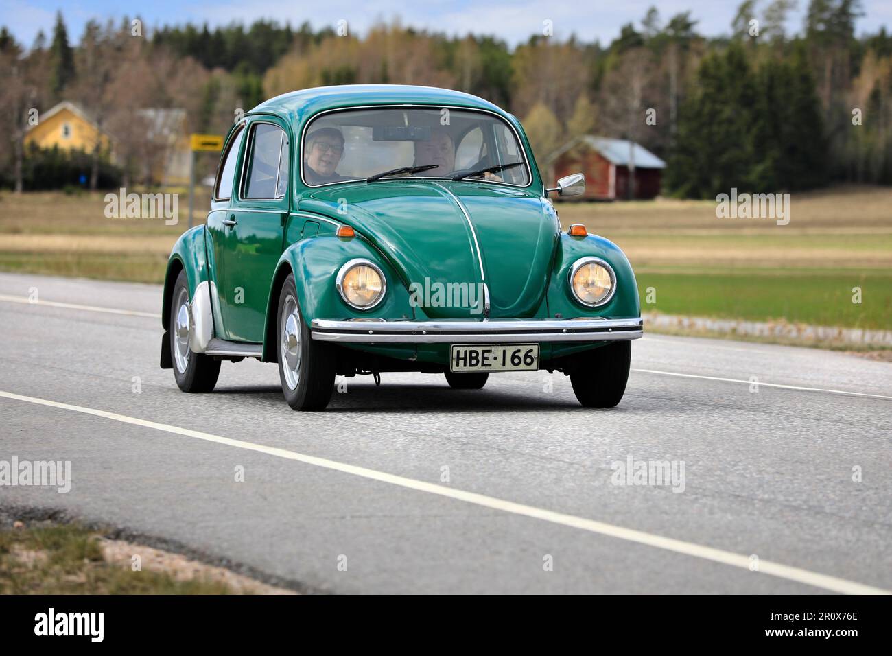 Green 1973 Volkswagen Beetle, officially Volkswagen Type 1, driving along Highway 110 on May Day car cruising event. Salo, Finland. May 1, 2023. Stock Photo