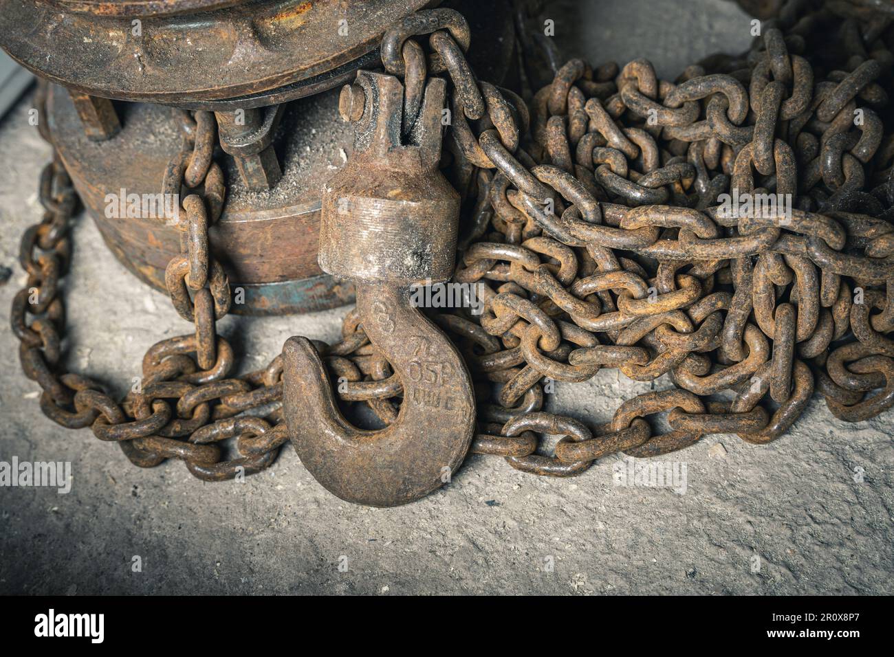 an old iron chain hoist with chain. a large hook for lifting loads