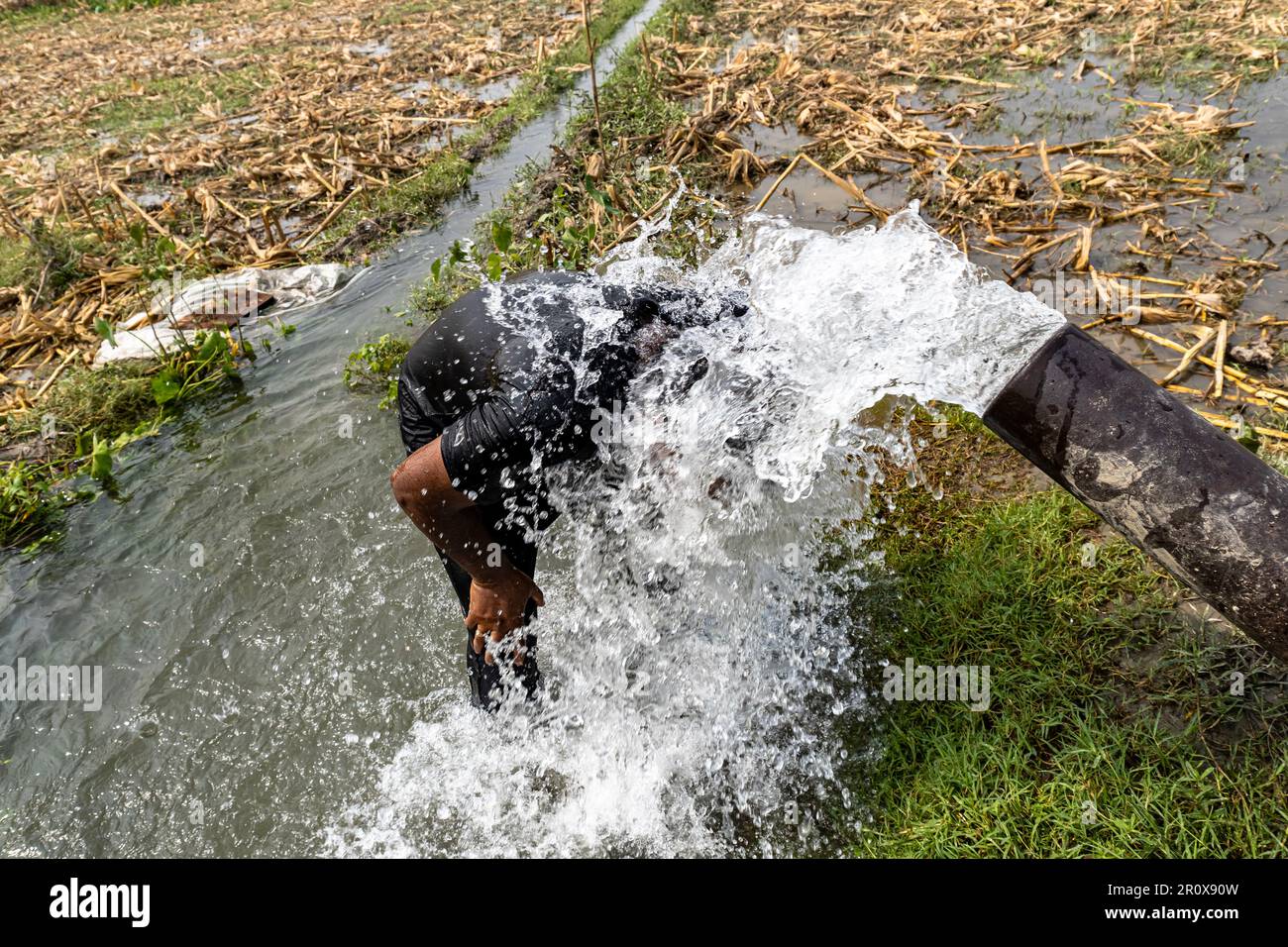Man taking a shower washing hair under water falling from motor water drops. Cleaning with high presure motor water in summer hot midday Stock Photo