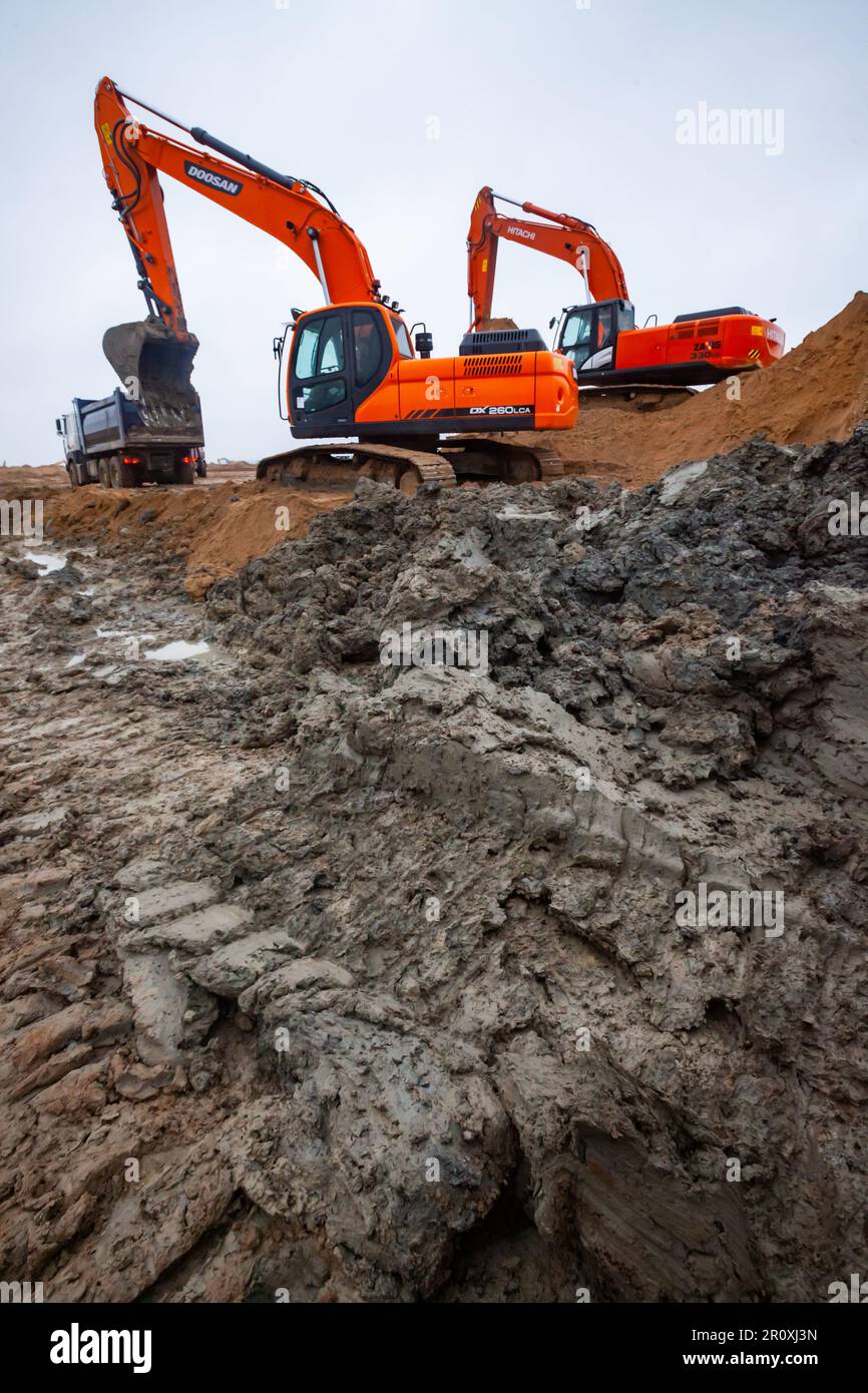 Ust-Luga, Leningrad oblast, Russia - November 16, 2021: Orange excavators Doosan on the dirty ground Stock Photo