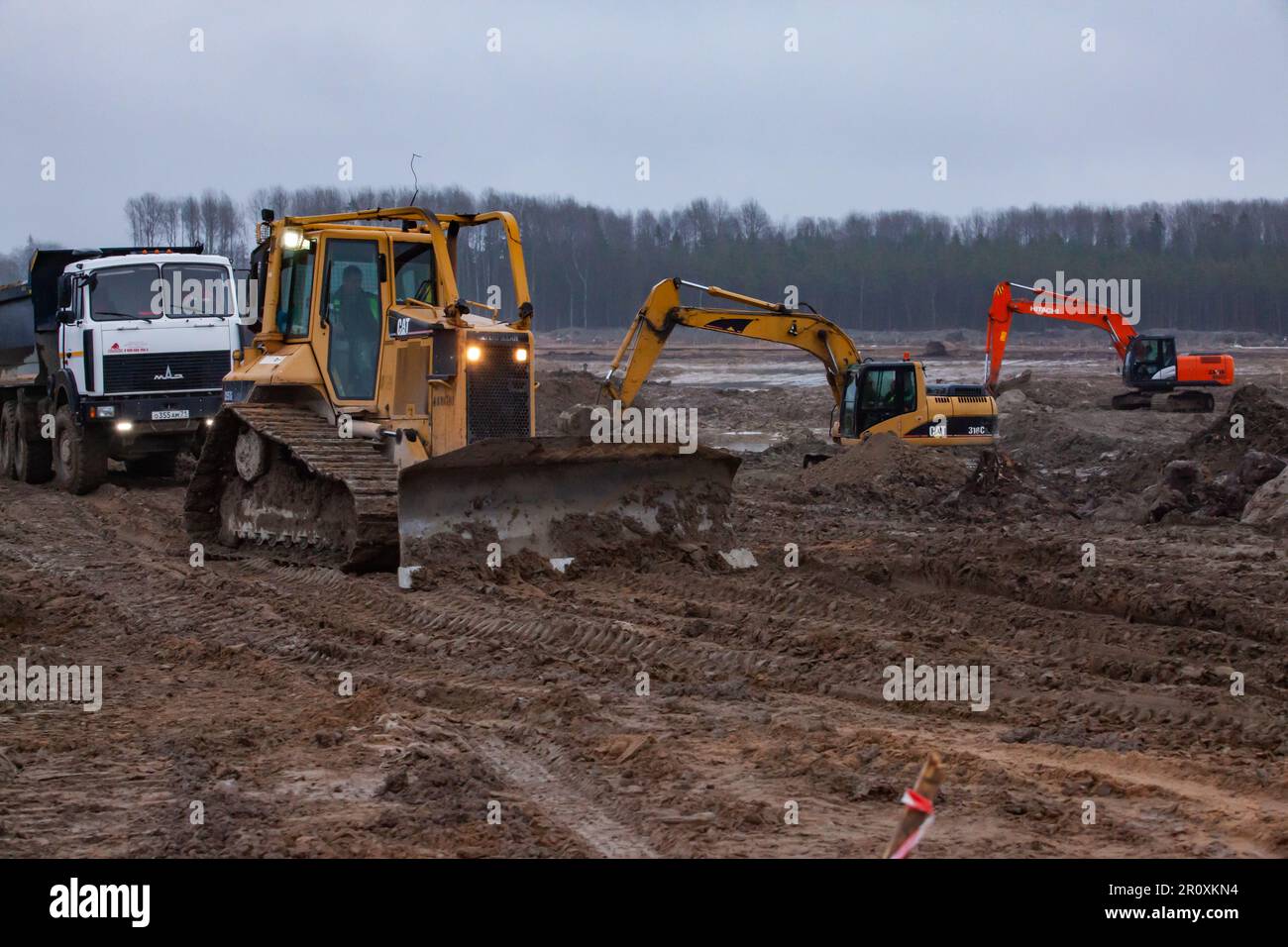 Ust-Luga, Leningrad oblast, Russia - November 16, 2021: Construction site on swamp. Traffic on muddy ground road of construction site. Bulldozer, exca Stock Photo