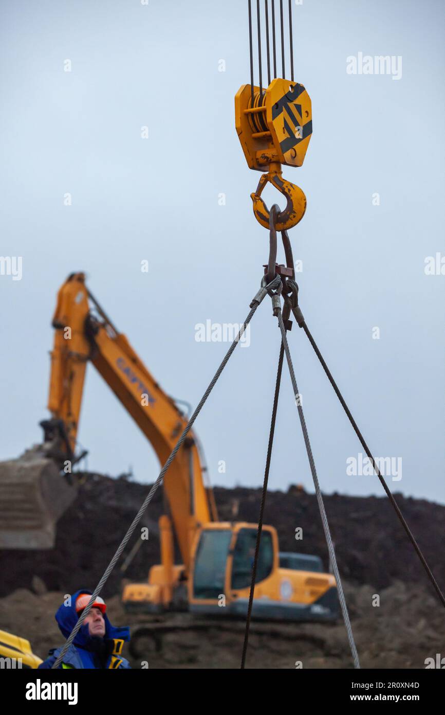 Ust-Luga, Leningrad oblast, Russia - November 16, 2021: Lifting weights with mobile crane. Worker operator is out of focus Stock Photo