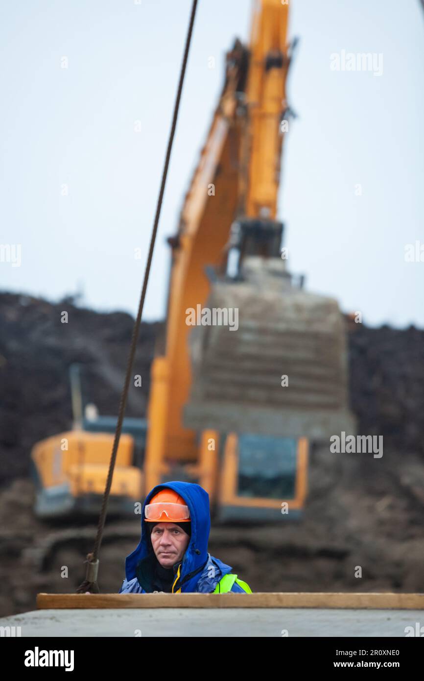 Ust-Luga, Leningrad oblast, Russia - November 16, 2021: Worker controls mobile crane on construction site. Stock Photo