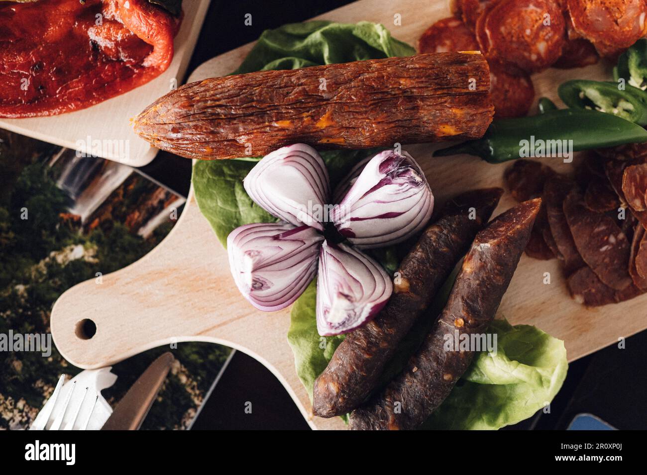 A wooden cutting board with a variety of cured meats. Stock Photo