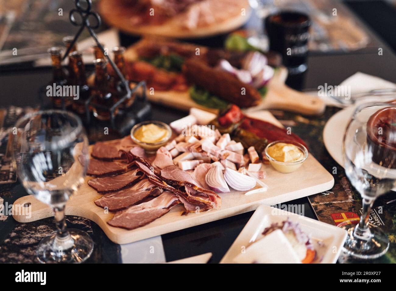 A wooden cutting board with a variety of cured meats. Stock Photo