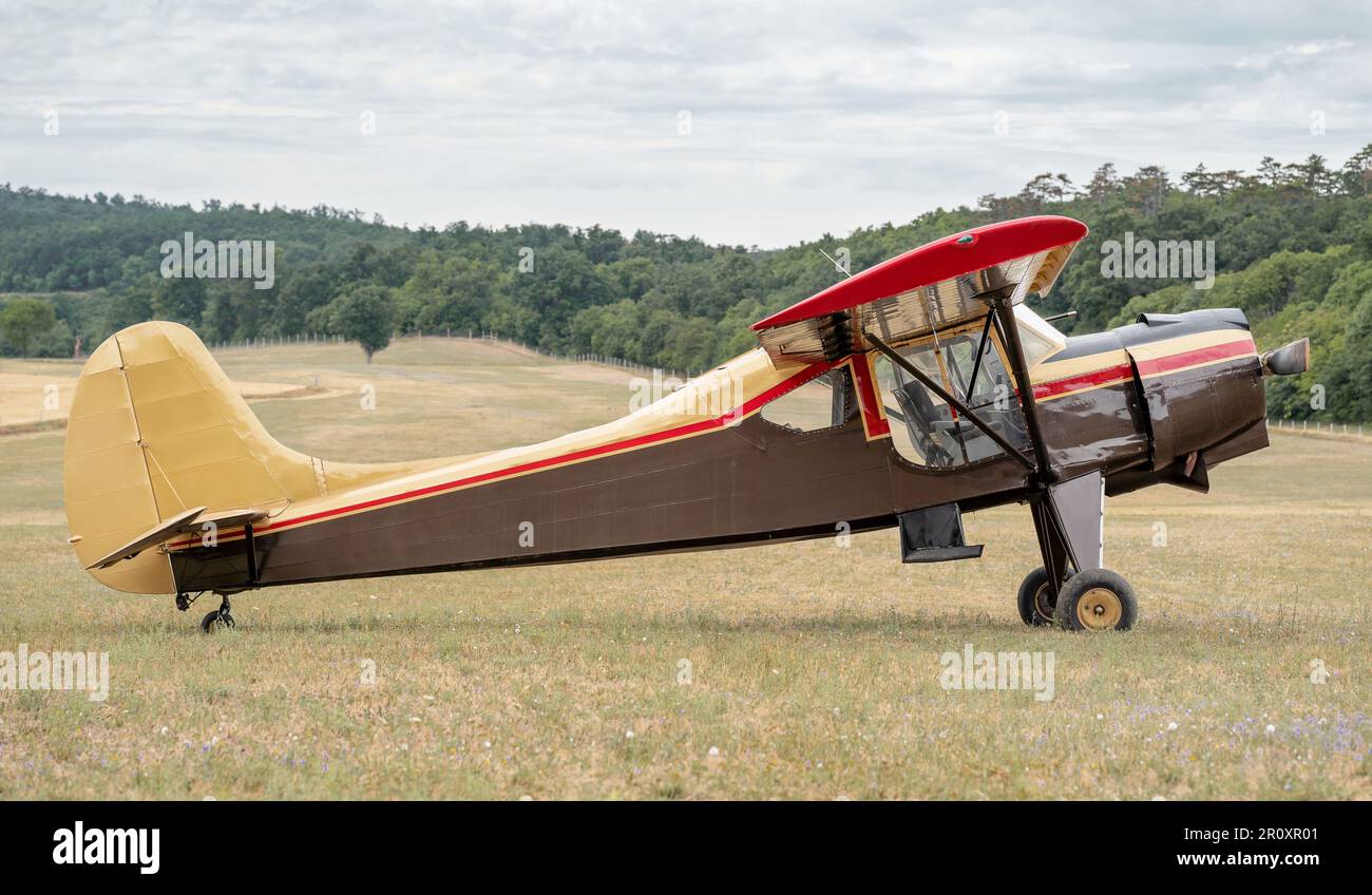 Old vintage classic airplane on the field. Biplane. Nine cylinder radial engine. Landscape in the background. Stock Photo