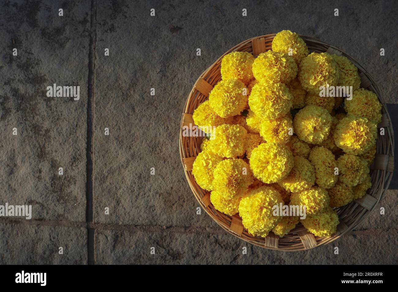 Fresh Marigold flowers bunch in wicker basket on floor background with blank space Stock Photo