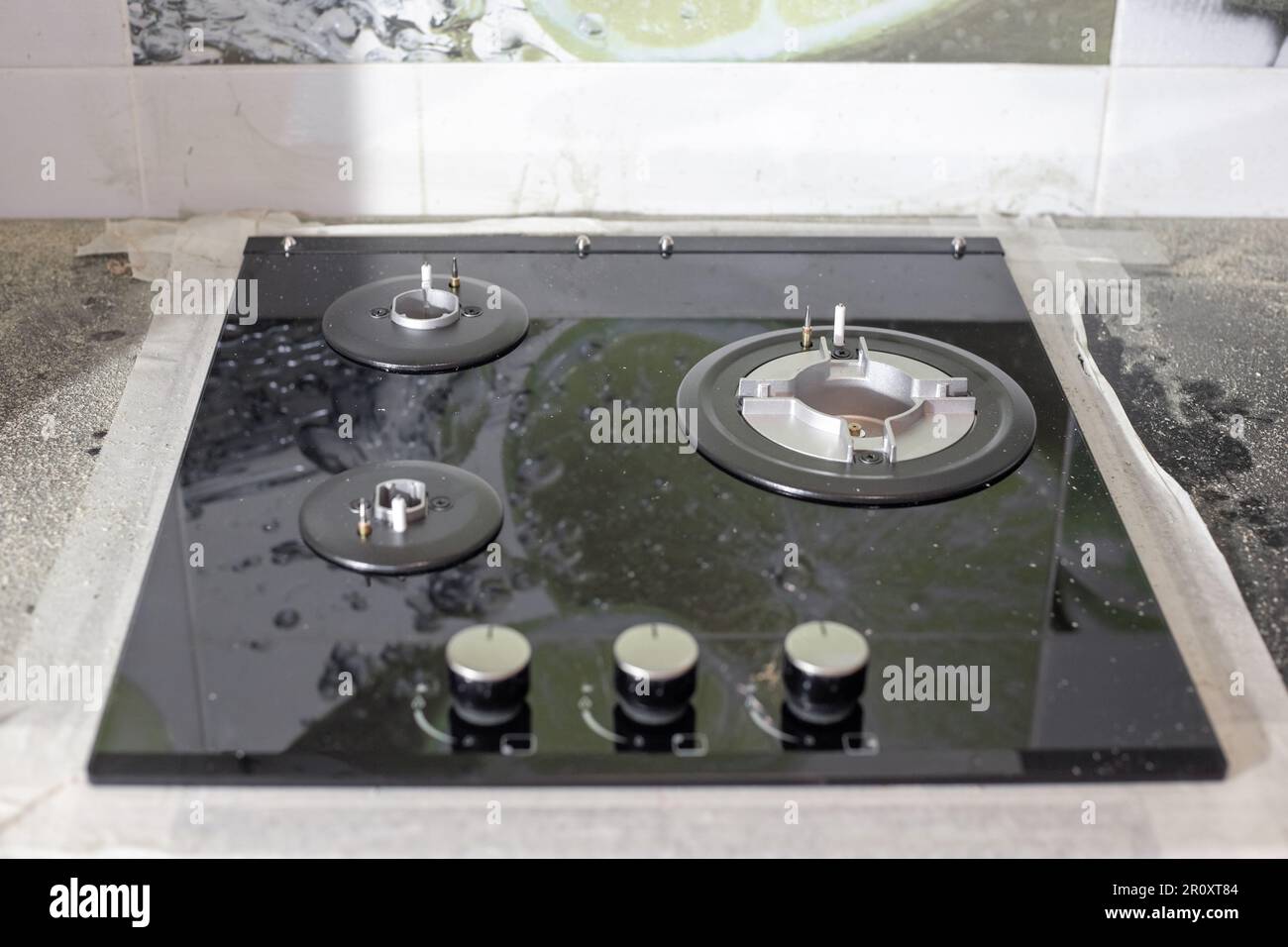 The black glassceramic gas hob is built into the kitchen worktop. Installation of a builtin