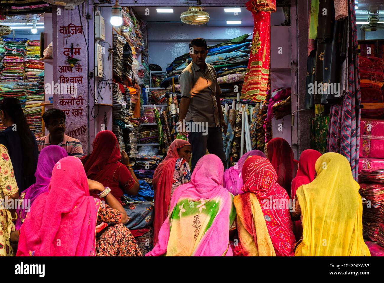 Fabric clothes vendor showing new samples to local women in Sadar Market. Jodhpur, Rajasthan, India Stock Photo