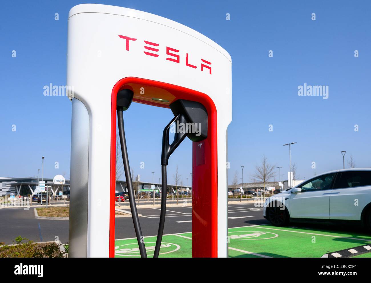 Tesla cars charging at Tesla Superchargers at a motorway service station in England. Stock Photo