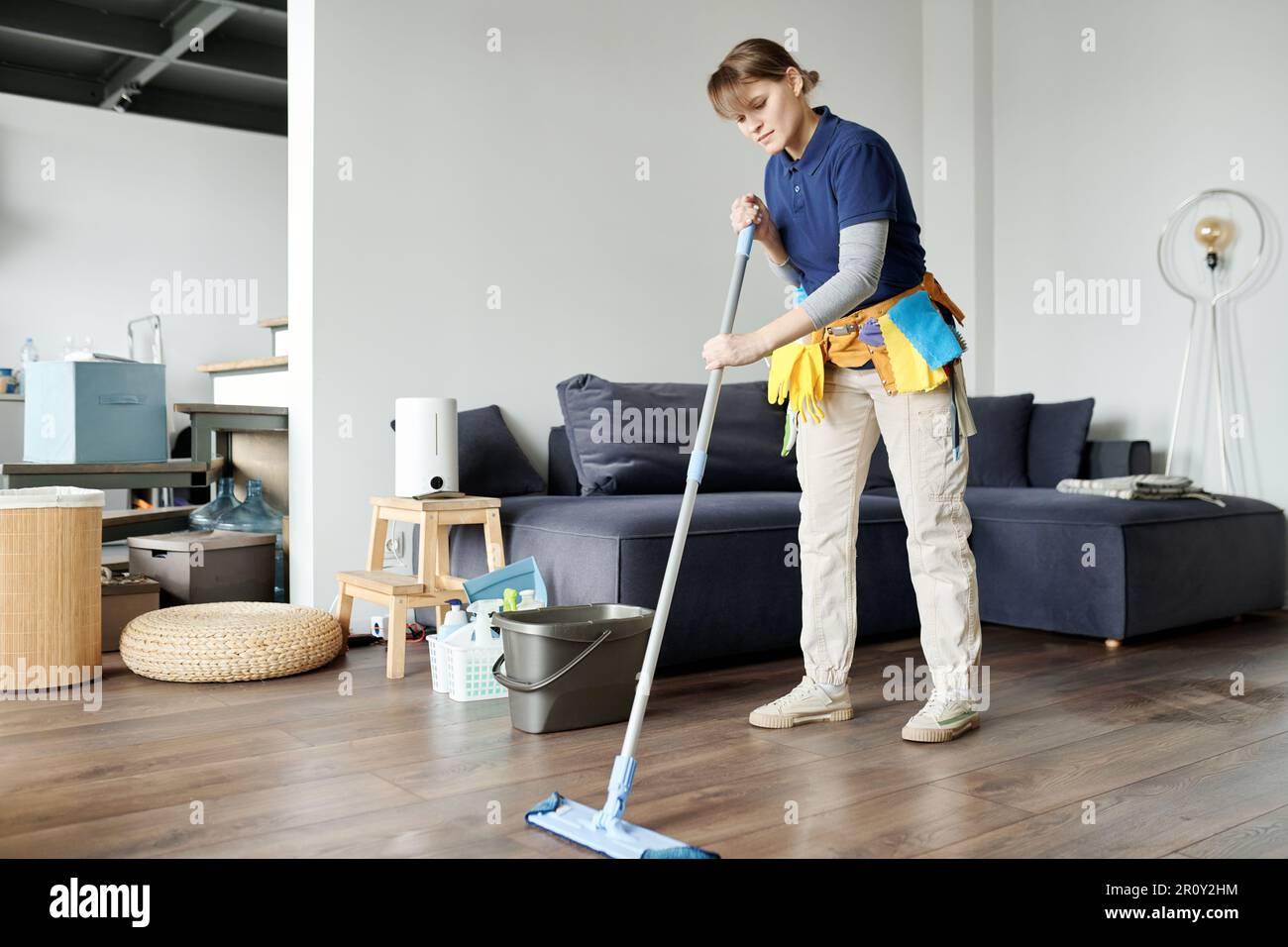 Cleaning service worker using mop to wipe the floor while doing