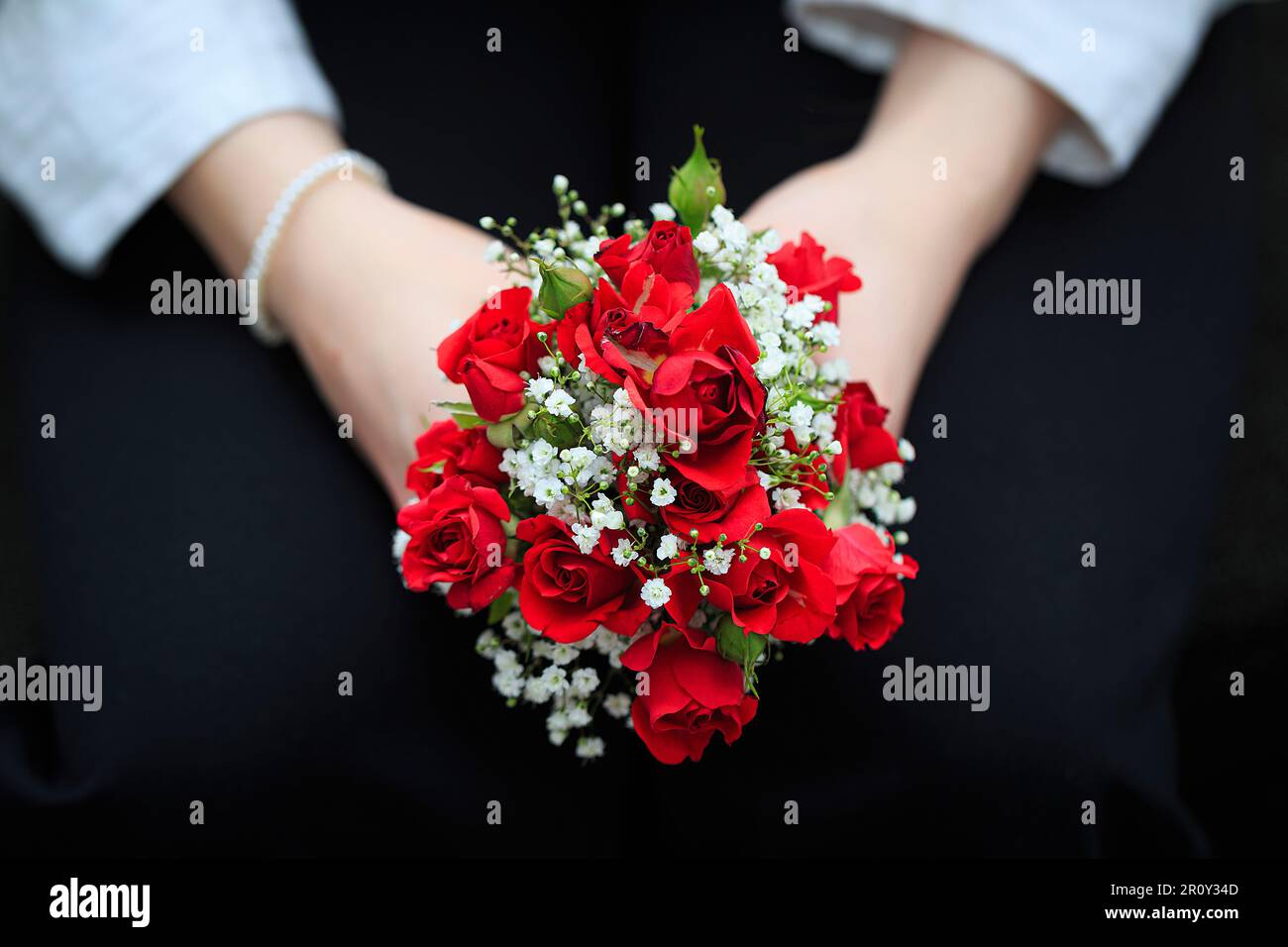 zwei Hände halten einen kleinen roten Rosenstrauß Stock Photo
