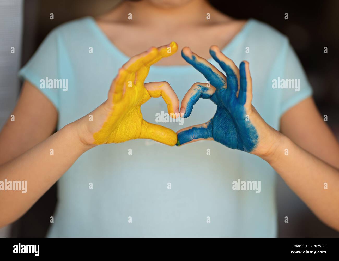 Child's hands painted on Ukraine flag colors. Peace for Ukraine. Stop war in Ukraine. Love Ukraine concept. Yellow and blue. Child's hands in a shape Stock Photo