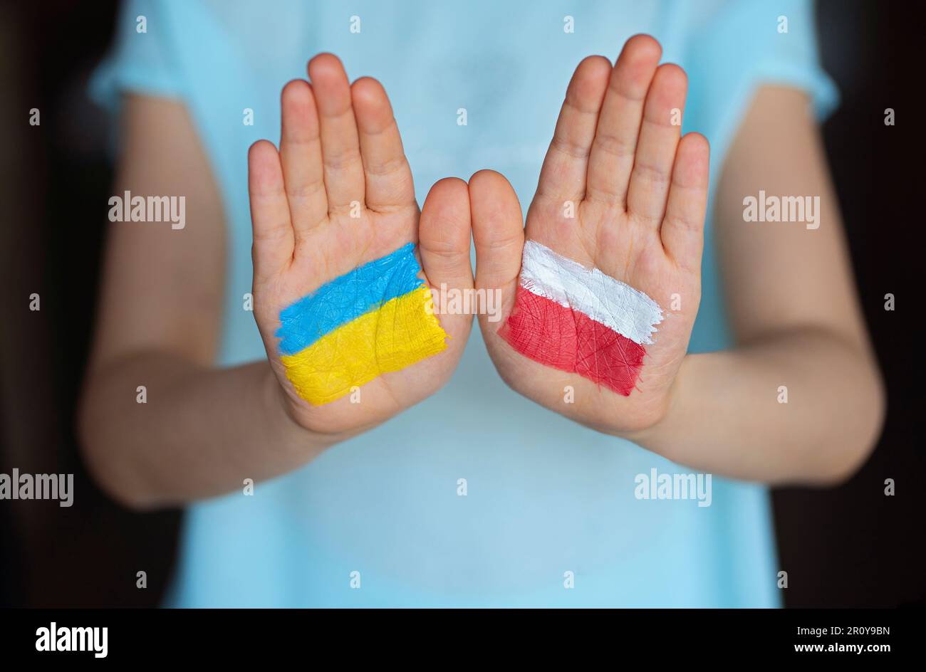 Child's hands painted in flags colors. Ukraine and Poland. Poland helps Ukraine. Friendship symbol. UA love concept. Peace for Ukraine. Stop war in Uk Stock Photo