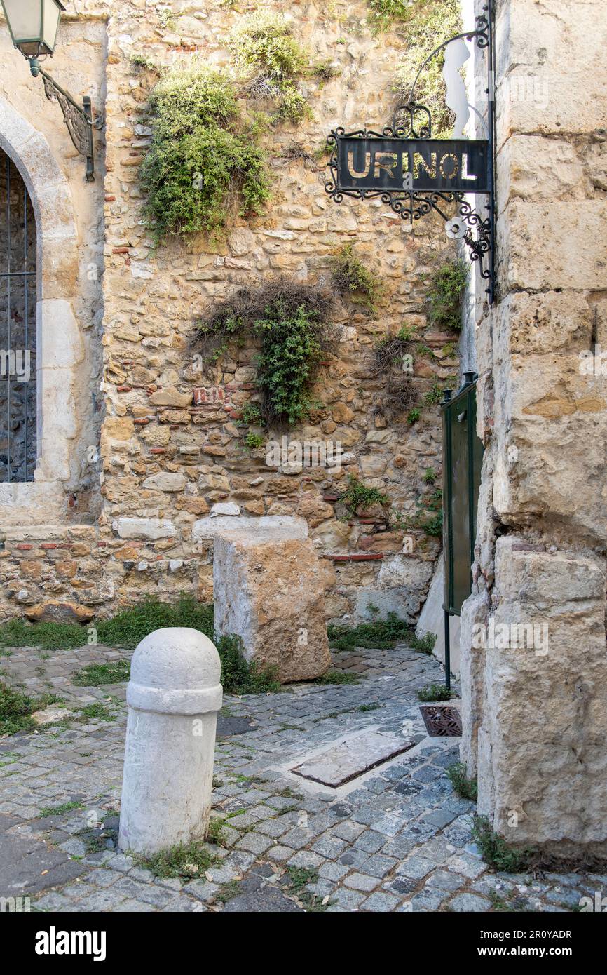 Vertical view of old fashioned public restroom or urinoir (Portuguese: urinol) for man with iron signage build in historic walls of Belmonte Palace Stock Photo