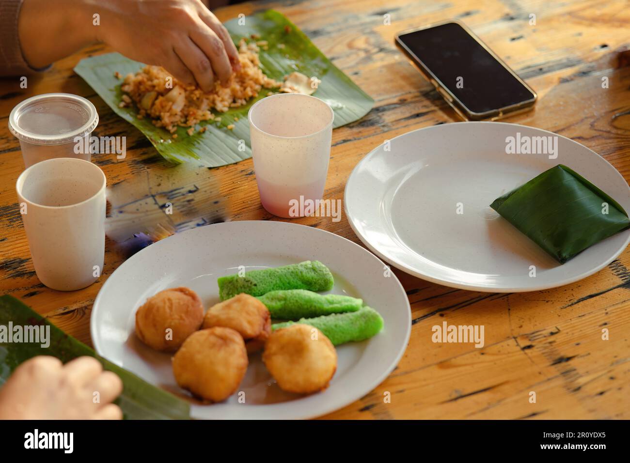 Malaysian staple breakfast on the table. Nasi lemak with Sweet desserts with coconut known as kuih ketayap and burger mini. Stock Photo