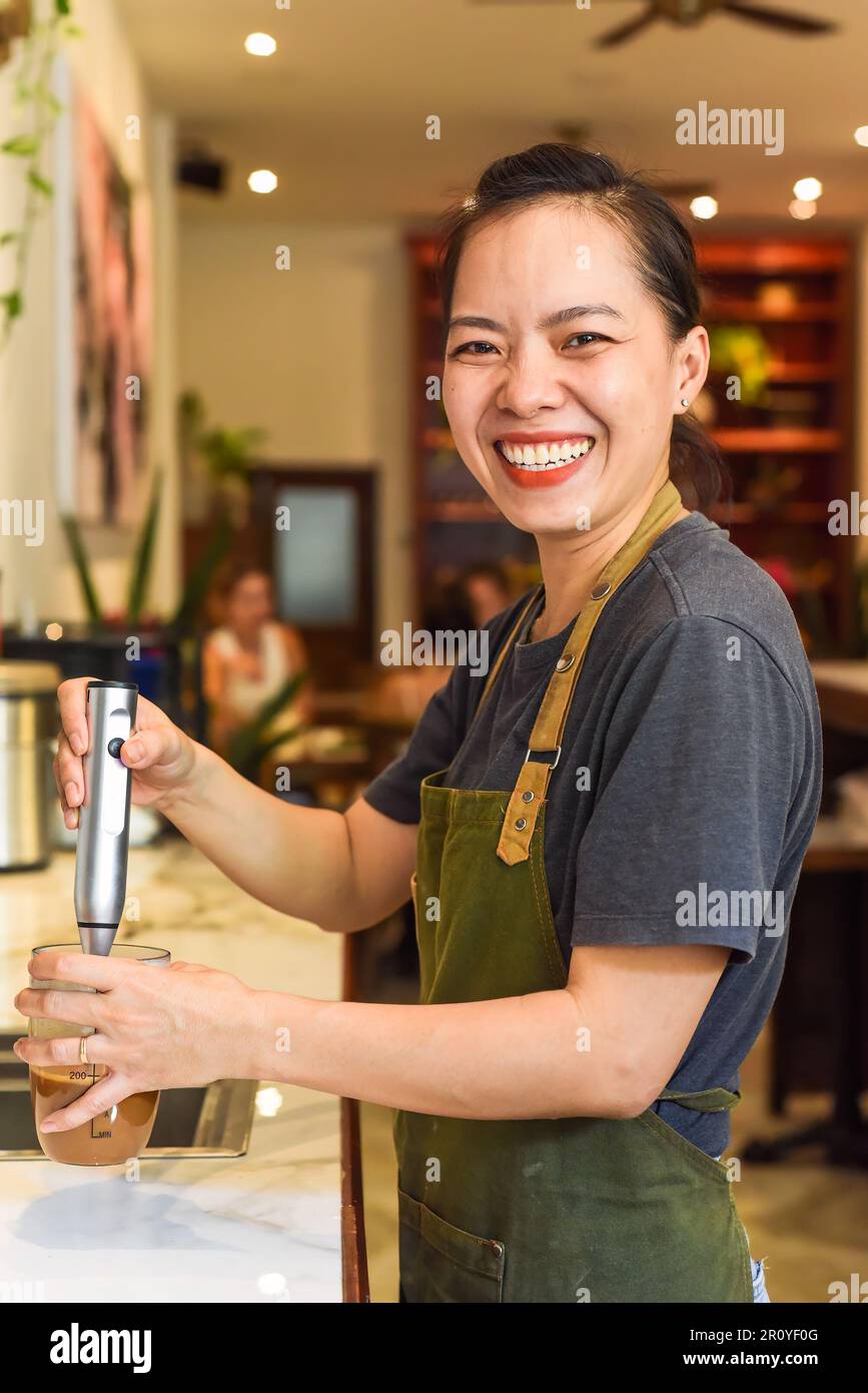 Vietnamese barista using a mixer for condensed milk in glass cup for