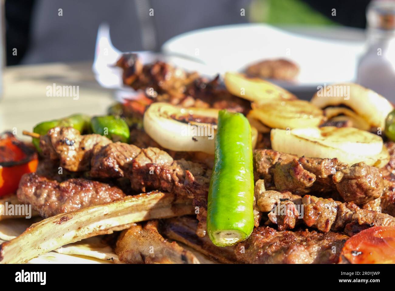 Close up delicious mixed kebab meat chopsteak meatball skewer lamb with vegetables pepper tomato onion near bread. Selective focus of area. Stock Photo