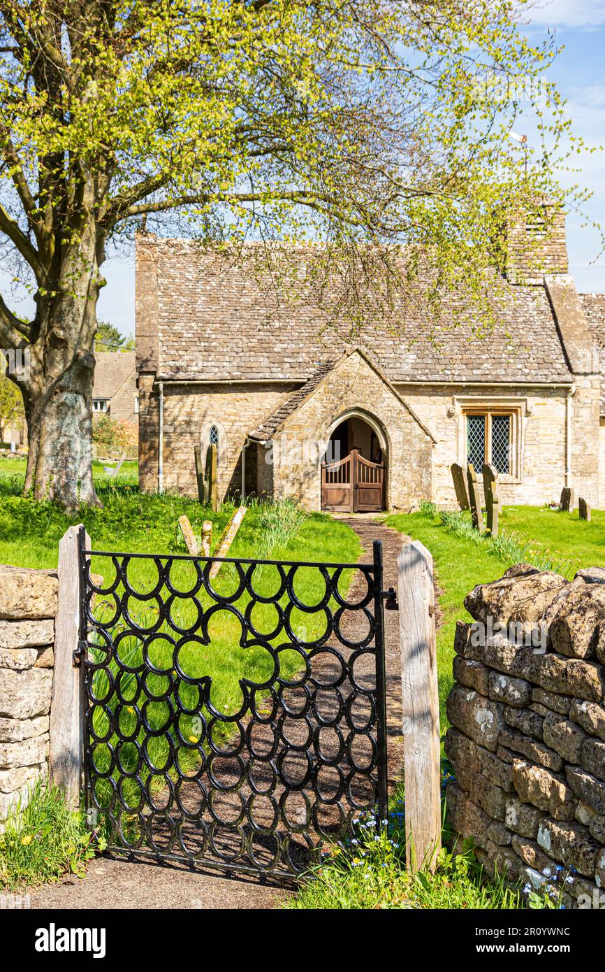 Church of St. James in the Cotswold village of Clapton-on-on-the-Hill, Gloucestershire UK. Wrought iron horseshoe gate was made by Raymond Phillips. Stock Photo