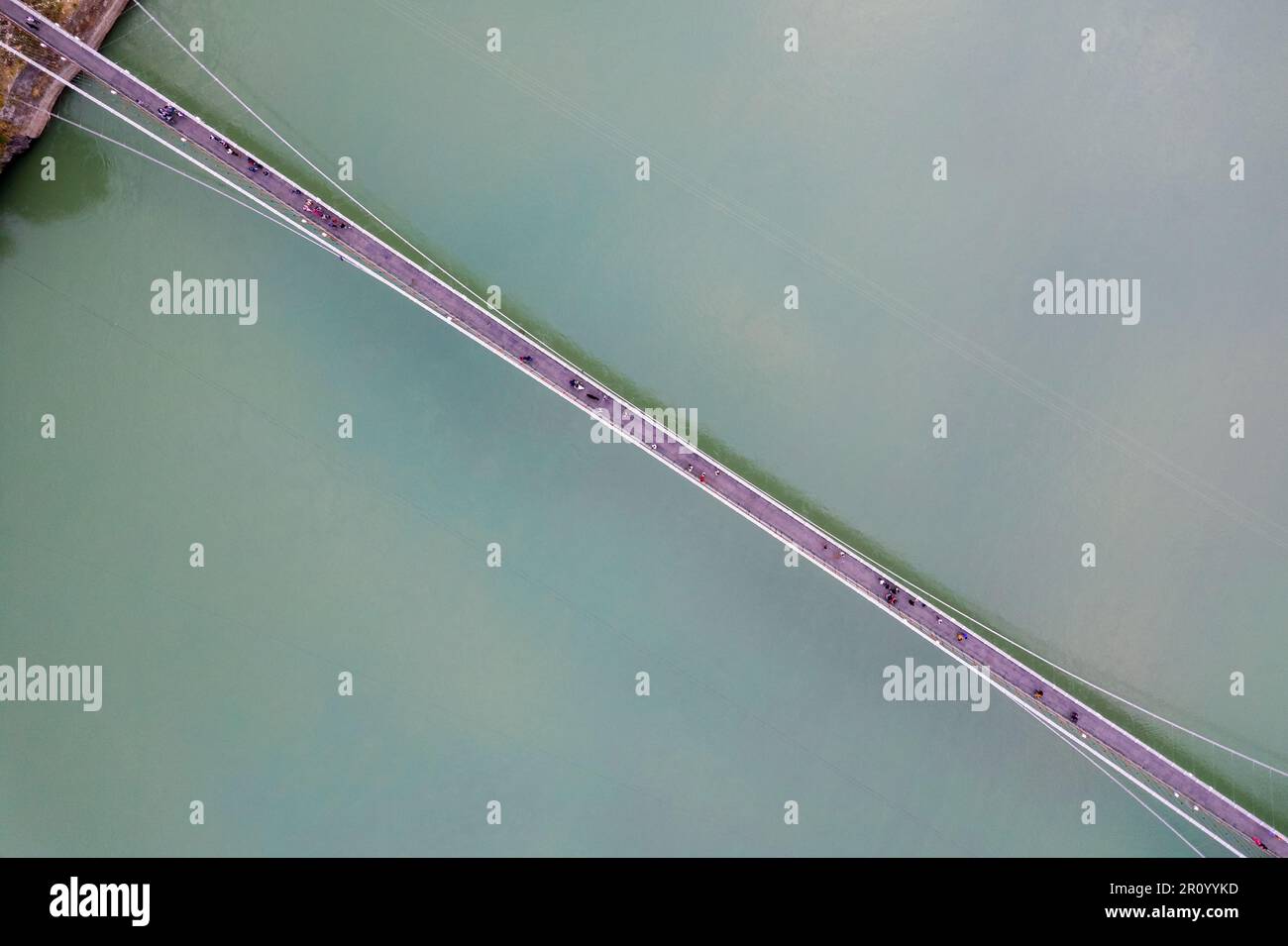 straight down decending aerial drone shot of ram setu suspension bridge over the fast flowing blue waters of ganga in the holy city of rishikesh Stock Photo