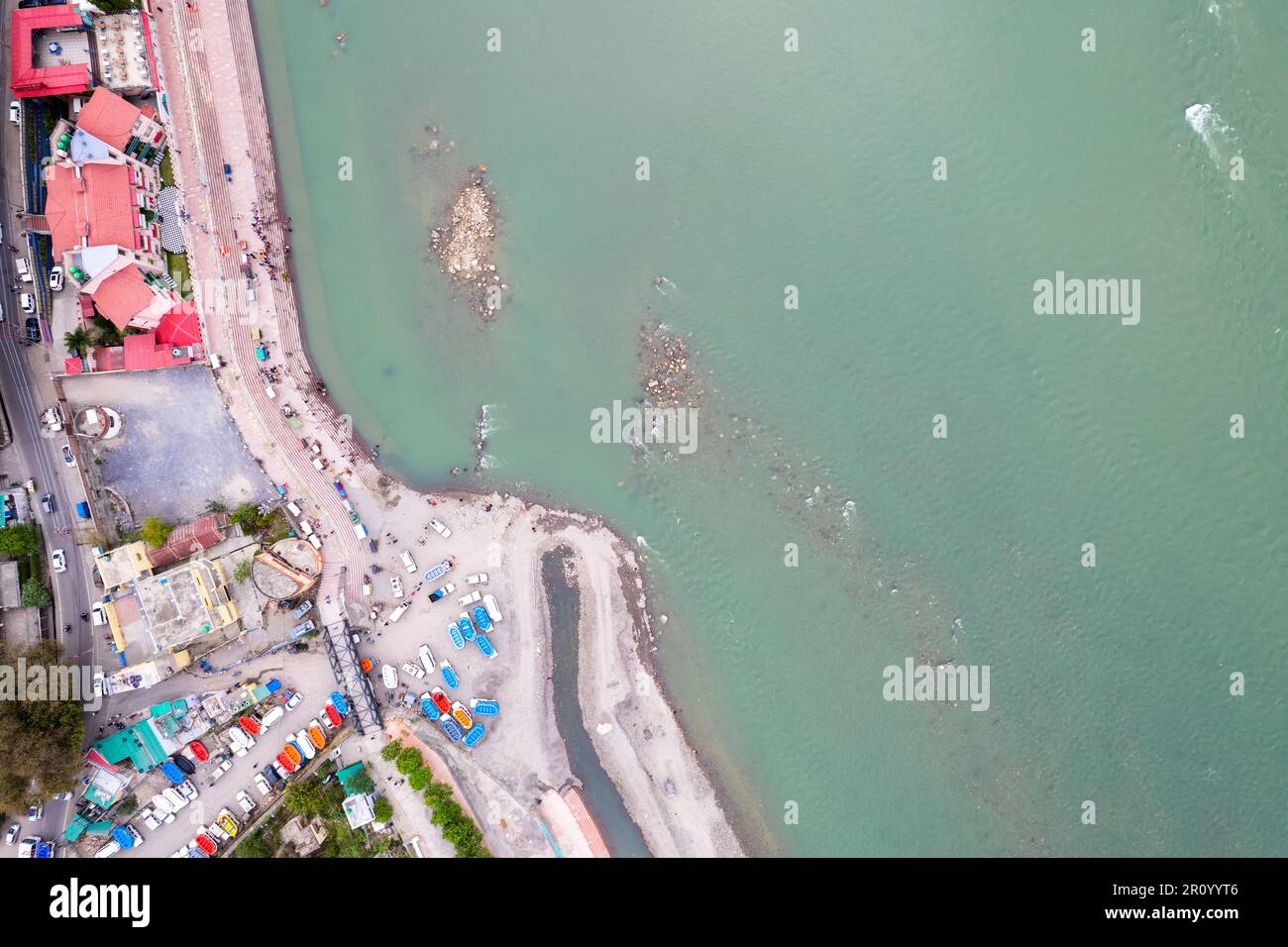 aerial drone shot showing rafts for water adventure sports on the blue waters of ganga river in rishikesh with people watching from the ghats on the Stock Photo