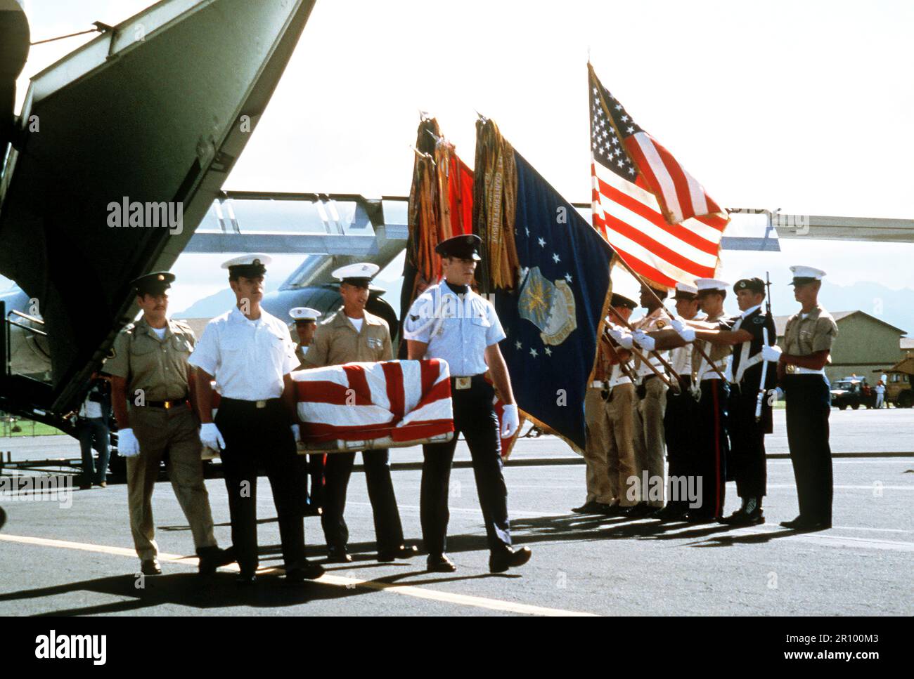 Joint-service pallbearers transfer flag-draped coffins of missing in action (MIA) soldiers to buses upon the arrival in Hawaii of the airlift returning them from Vietnam. Stock Photo