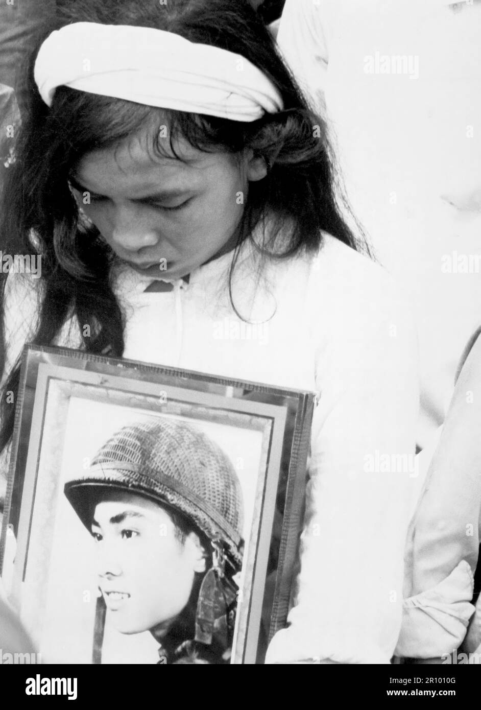 Almost 400 men, women and children massacred by the Viet Cong during 'Tet 1968' were mourned at a common-grave burial on October 14.  This young widow, carrying a photograph of her missing husband, mourns at the mass funeral service in Hue. Stock Photo