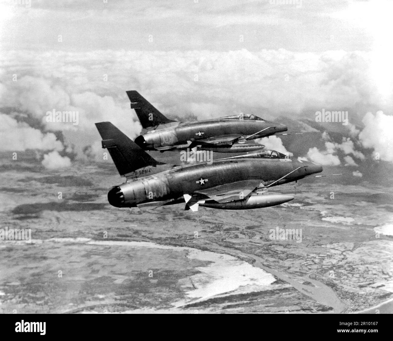 An air-to-air right rear view of two F-100D Super Sabre aircraft streaking over South Vietnam on their way to an assigned target.  The aircraft provides much of the tactical air support to Allied ground forces fighting in Vietnam. Stock Photo