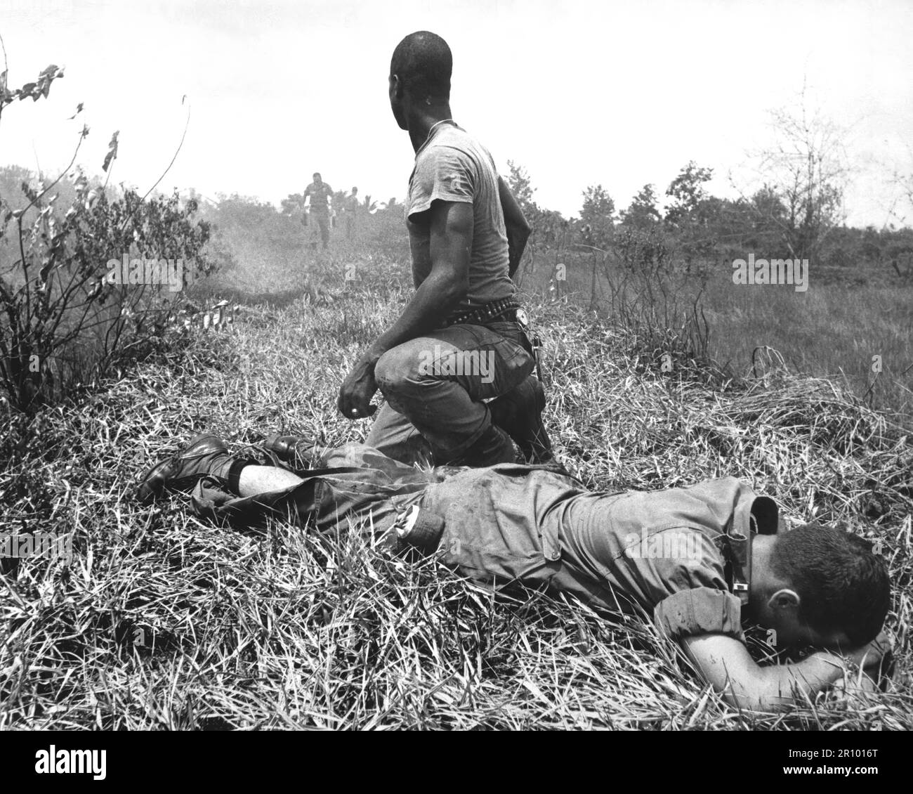 A young American lieutenant, his leg burned by an exploding Viet Cong white phosphorus booby trap, awaits a Medevac helicopter while treated by a medic.  Circa 1966. Stock Photo