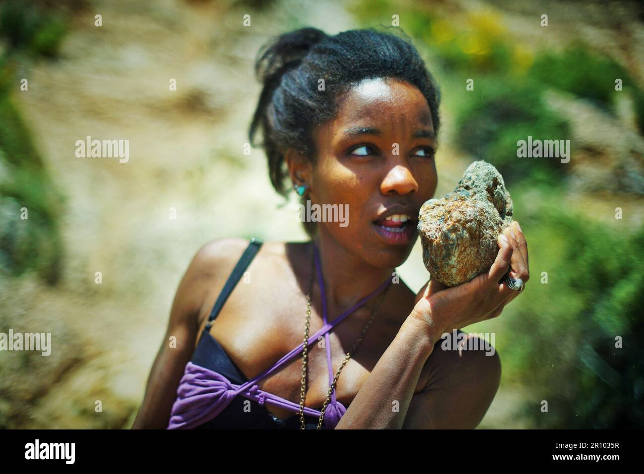Beautiful Black woman in purple clothing stranded on a desert island Stock Photo