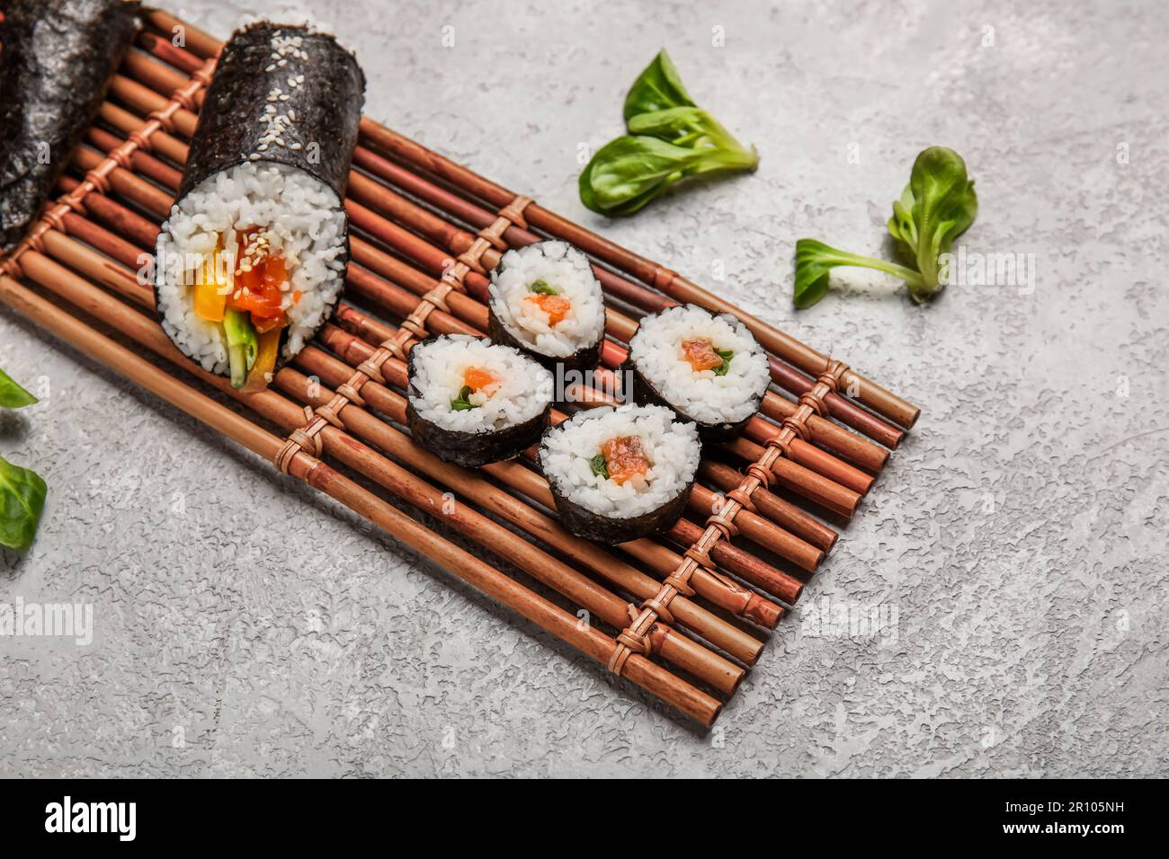 https://c8.alamy.com/comp/2R105NH/bamboo-mat-with-tasty-sushi-rolls-on-grunge-background-2R105NH.jpg